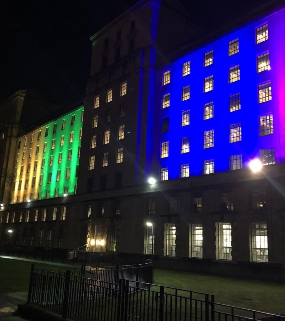 Image of the Ministry of Defence in London, lit up in different colours, at night